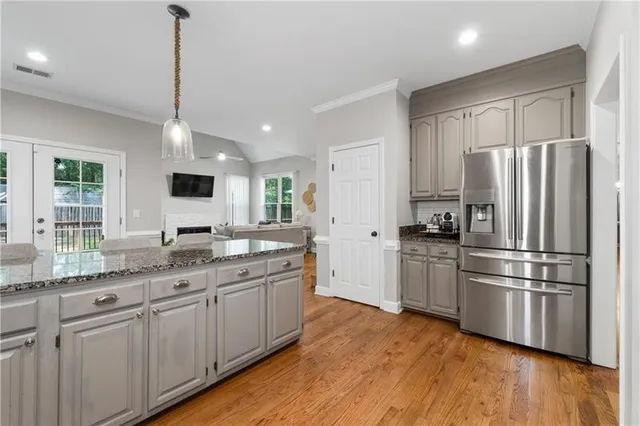 a kitchen with granite countertop a refrigerator and white cabinets