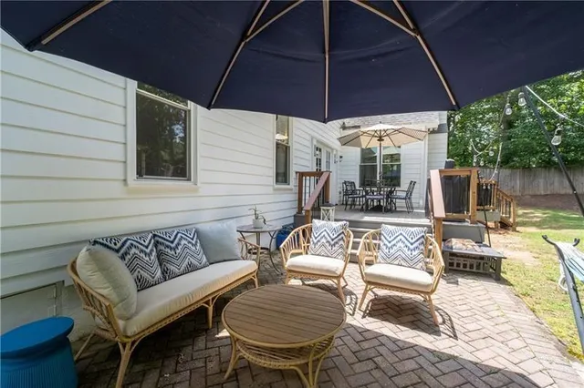a view of a patio with couches table and chairs under an umbrella