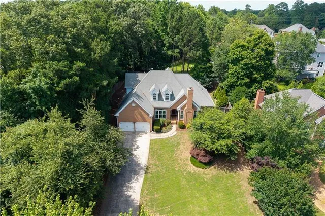 an aerial view of a house with a yard swimming pool and large trees