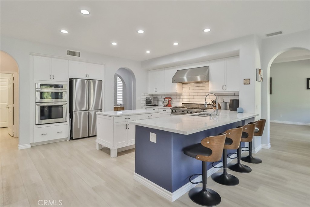 5421 Moonshadow Street Simi Valley, CA 93063 - Photo 17 of 56 a kitchen with stainless steel appliances kitchen island hardwood floor sink and stove