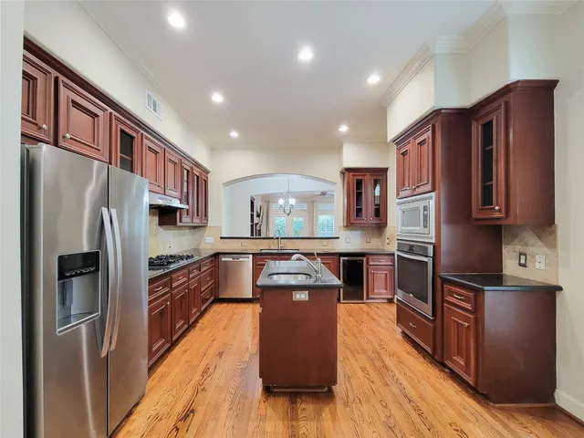 a kitchen with stainless steel appliances granite countertop a sink a stove and a wooden cabinets