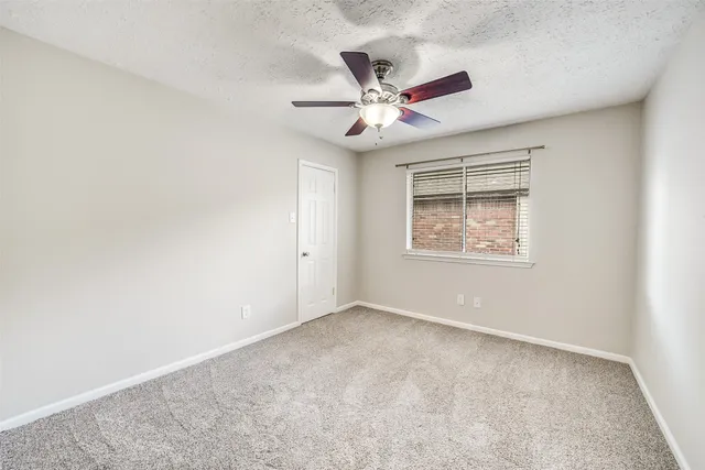 an empty room with a window and a fan