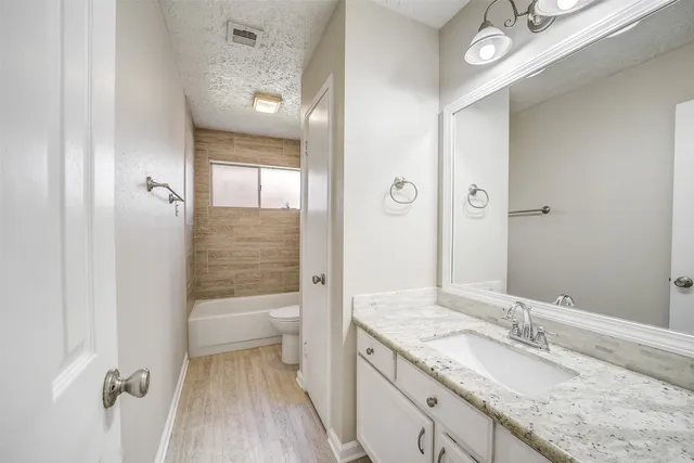 a bathroom with a granite countertop sink a toilet and shower