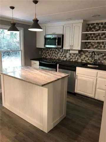 a kitchen with stainless steel appliances granite countertop a sink a stove and a wooden floors