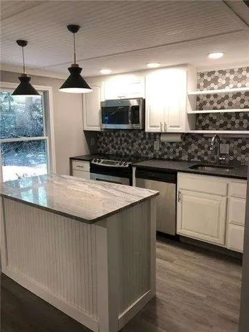 a kitchen with stainless steel appliances granite countertop a sink a stove and a wooden floor