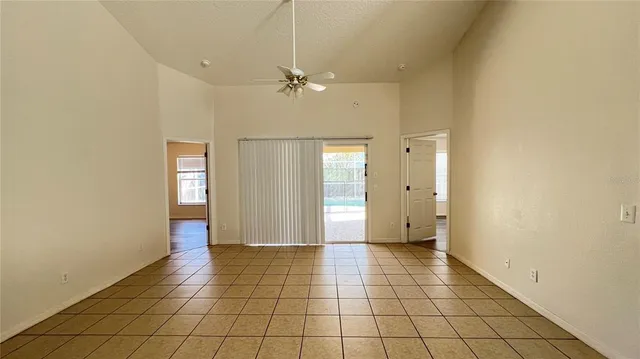a view of an empty room with window and chandelier fan