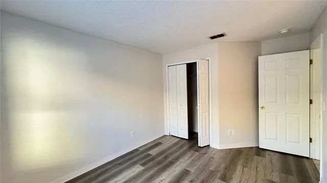 an empty room with wooden floor and closet area