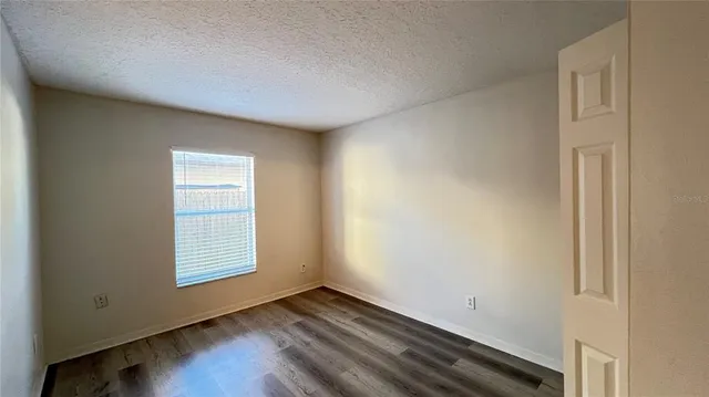 an empty room with wooden floor closet and windows
