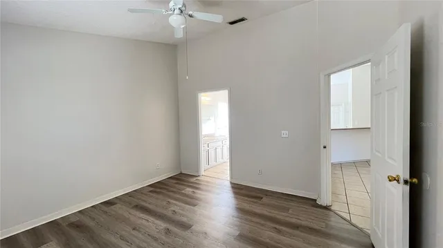an empty room with wooden floor and a ceiling fan
