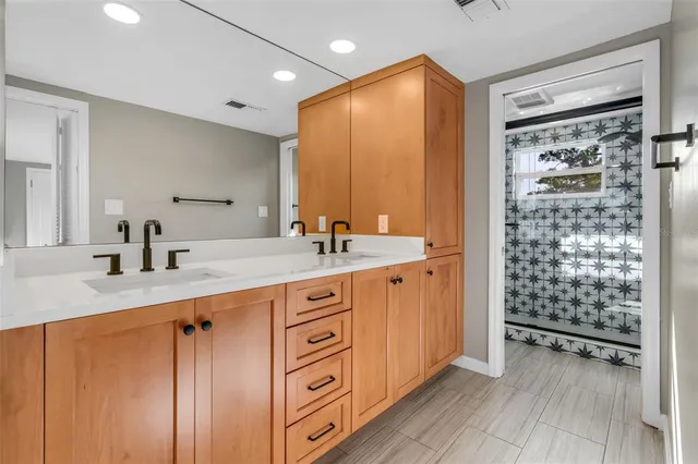 a spacious bathroom with a double vanity sink a mirror and shower