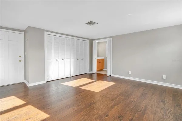 a view of an empty room with wooden floor and a window