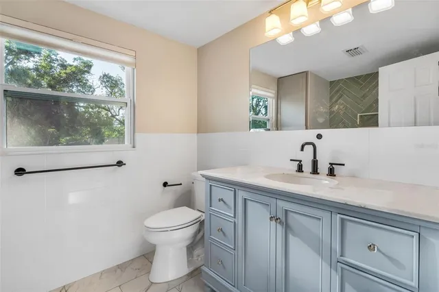 a bathroom with a granite countertop sink a toilet and a mirror
