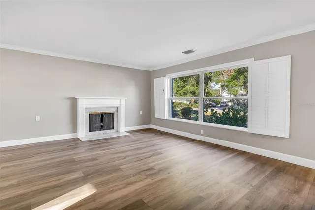a view of empty room with wooden floor and fireplace