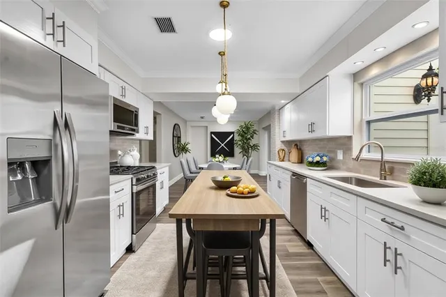a kitchen with stainless steel appliances a dining table and stove top oven