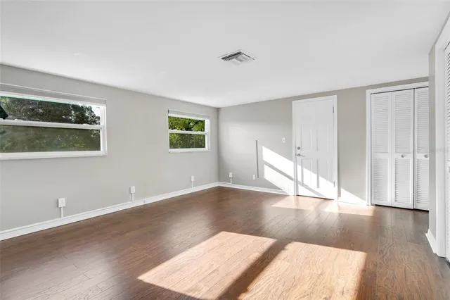 an empty room with wooden floor and windows