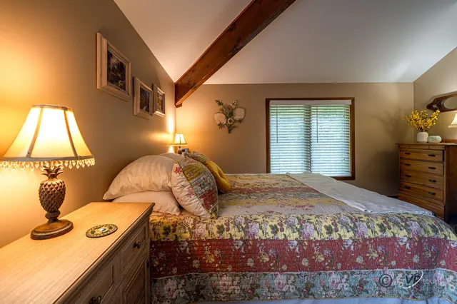 a bedroom with a bed and a lamp on the dresser
