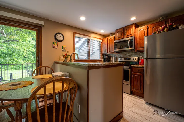 a kitchen with stainless steel appliances granite countertop a refrigerator a stove top oven a sink dishwasher and wooden cabinets