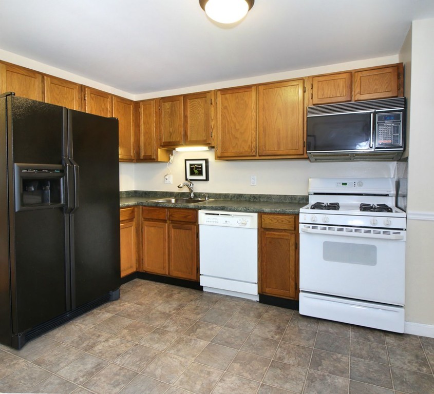 90 Roper Street, Unit D Lowell, MA 01852 - Photo 4 of 17 a kitchen with a stove microwave and refrigerator