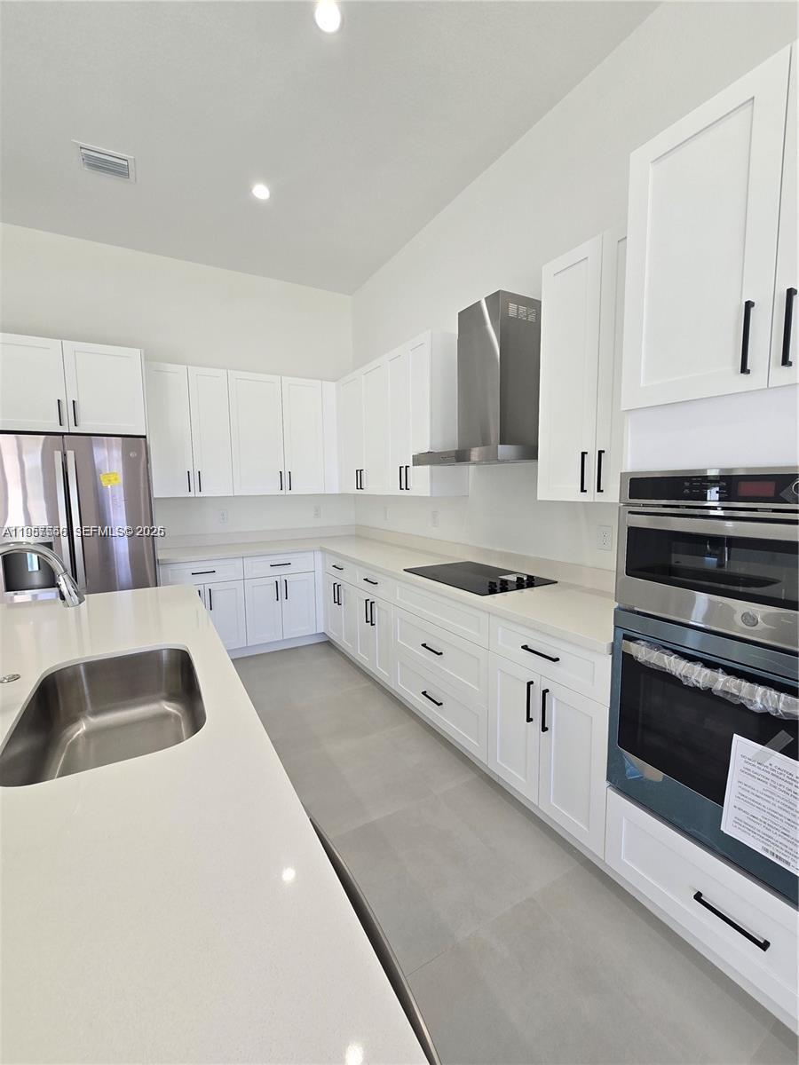 19534 Southwest 324th Street Homestead, FL 33030 - Photo 46 of 86 a kitchen with granite countertop a sink and white cabinets