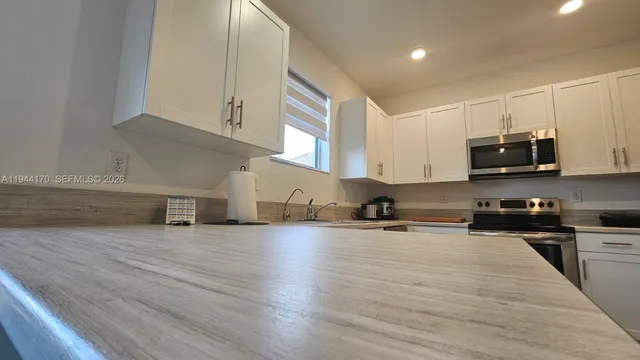 a kitchen with stainless steel appliances a stove a sink and white cabinets