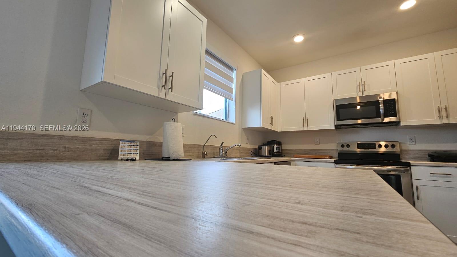 1146 Southeast 26th Street Homestead, FL 33035 - Photo 8 of 42 a kitchen with stainless steel appliances a stove a sink and white cabinets