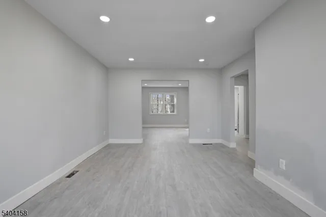 an empty room with wooden floor and window