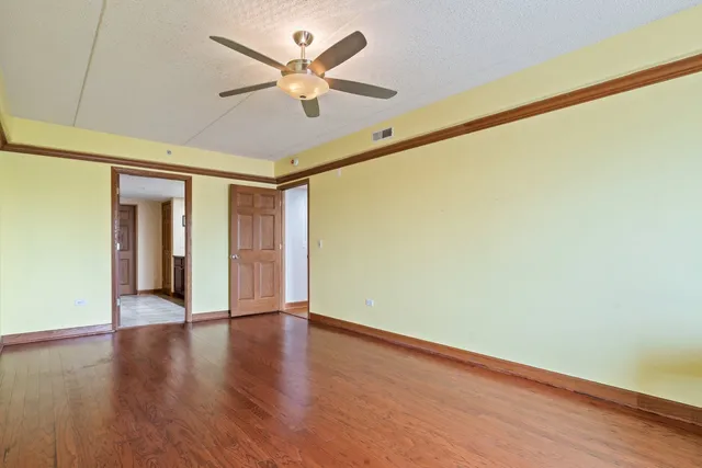 an empty room with wooden floor and a ceiling fan