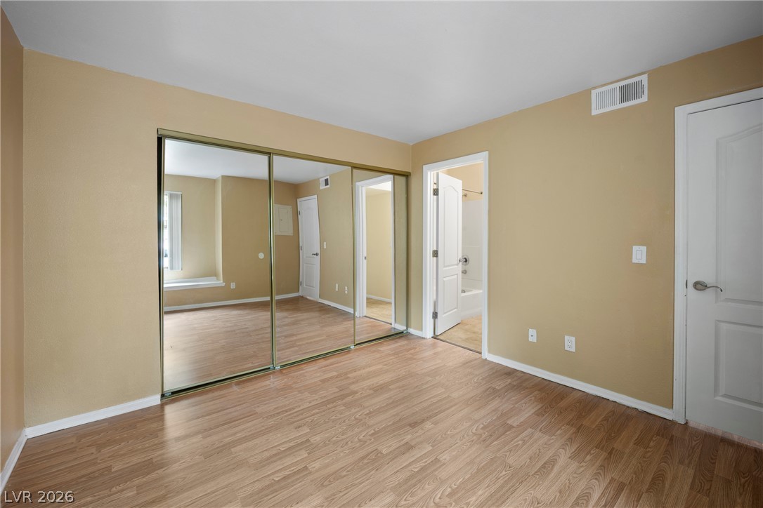 3145 East Flamingo Road, Unit 1055 Las Vegas, NV 89121 - Photo 19 of 40 Natural light illuminates this bedroom, offering ample closet space with mirrored sliding doors and durable laminate flooring.