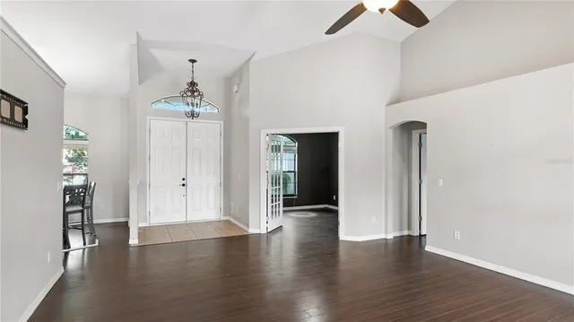 an empty room with wooden floor and ceiling fan
