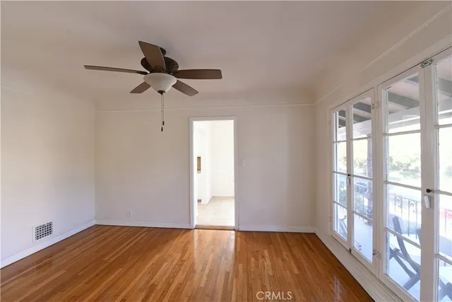 a view of empty room with wooden floor and fan