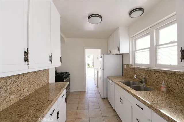 a large kitchen with a granite countertop cabinets a sink a window and stainless steel appliances