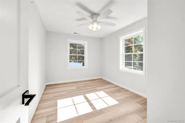 an empty room with windows and ceiling fan