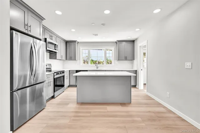 a kitchen with stainless steel appliances kitchen island granite countertop a refrigerator a sink a stove a microwave and island