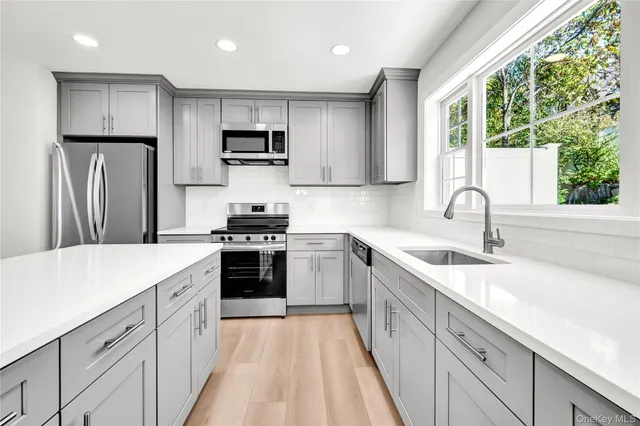 a kitchen with granite countertop a sink stainless steel appliances and window