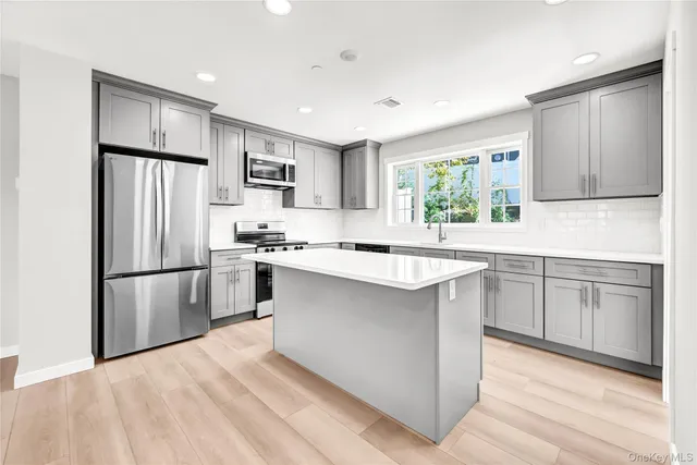 a kitchen with kitchen island granite countertop a refrigerator stove top oven and sink