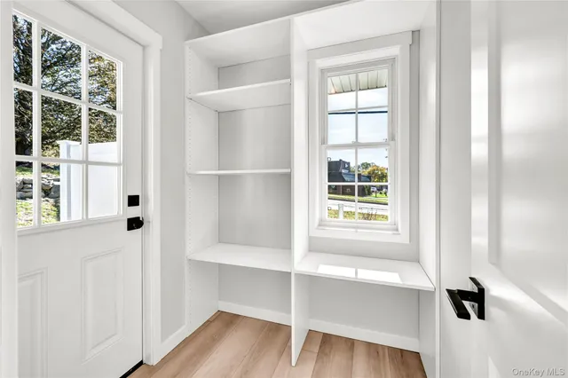 a view of an empty room with a window and wooden floor