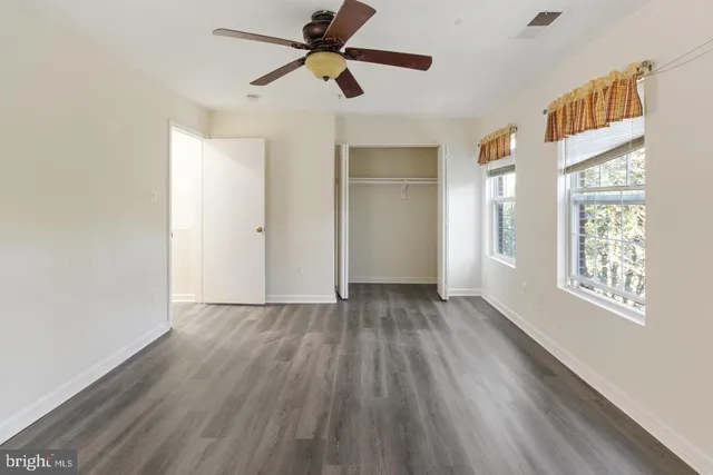 a view of empty room with wooden floor and fan