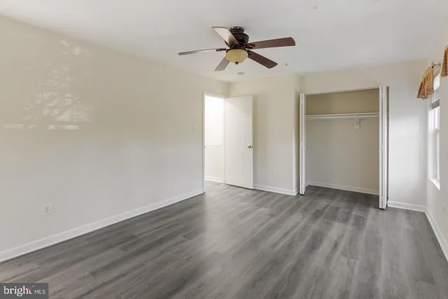 an empty room with wooden floor ceiling fan and windows