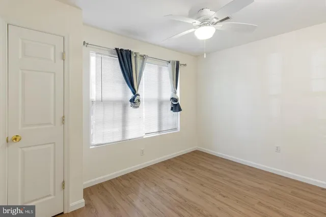 a view of empty room with wooden floor and fan