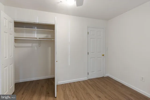 a view of an empty room with wooden floor & closet