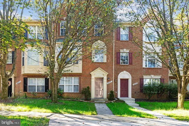 a front view of a house with garden and trees
