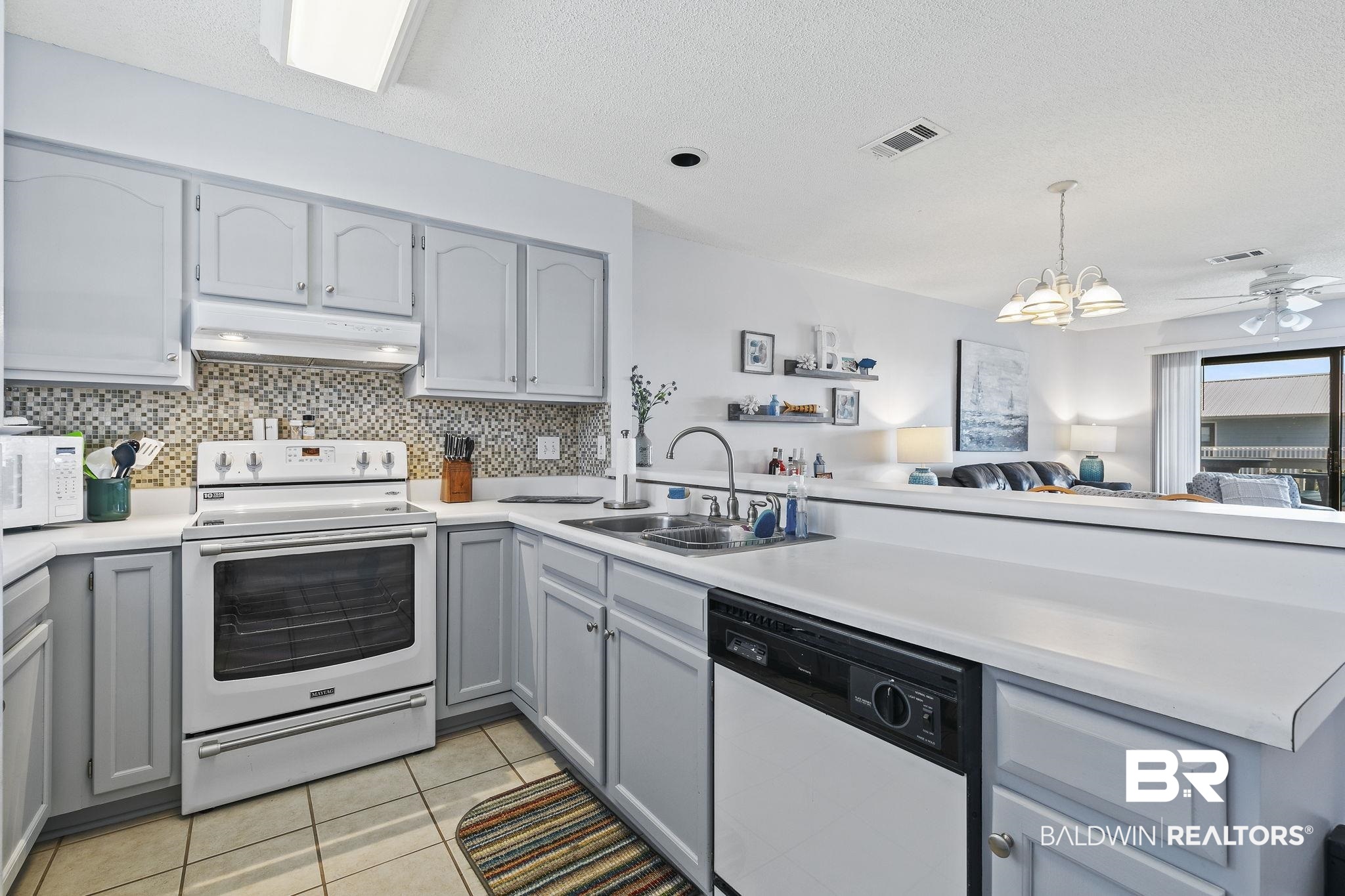 25861 Canal Road, Unit 78 Orange Beach, AL 36561 - Photo 9 of 45 Kitchen featuring visible vents, gray cabinets, under cabinet range hood, a sink, and white appliances