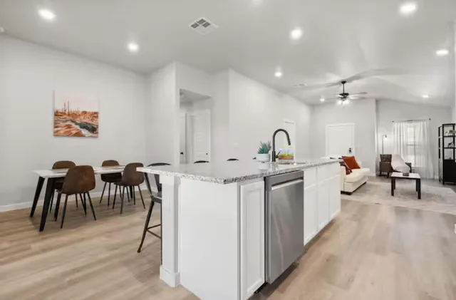 a large white kitchen with kitchen island a sink table and chairs