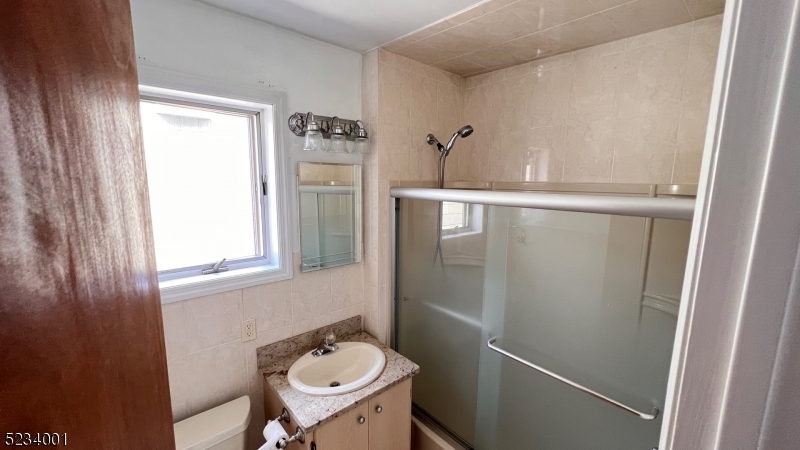74 Mill Street Bloomfield, NJ 07003 - Photo 3 of 10 a bathroom with a sink and mirror with toilet