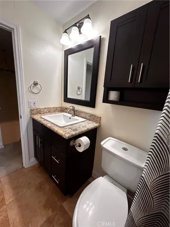 a bathroom with a granite countertop toilet sink and mirror