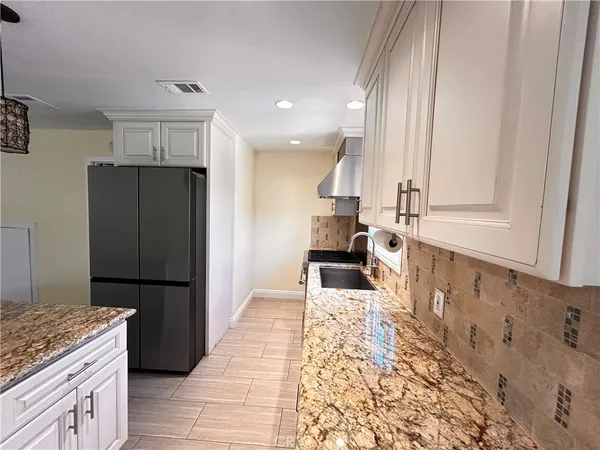 a kitchen with granite countertop a refrigerator and a sink