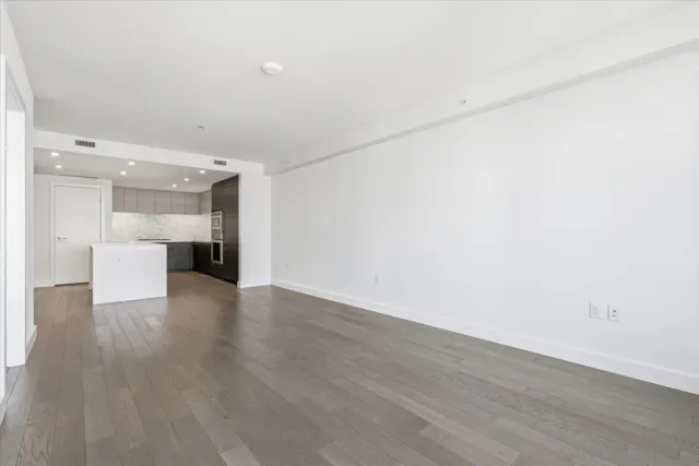 a view of a room with wooden floor and a kitchen