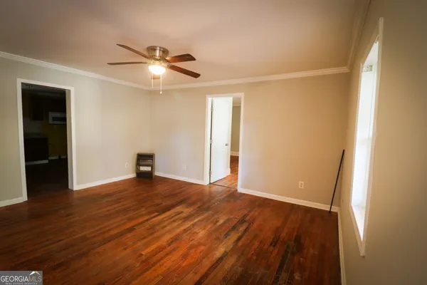 an empty room with wooden floor and windows