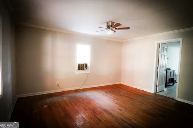 a view of empty room with wooden floor and fan