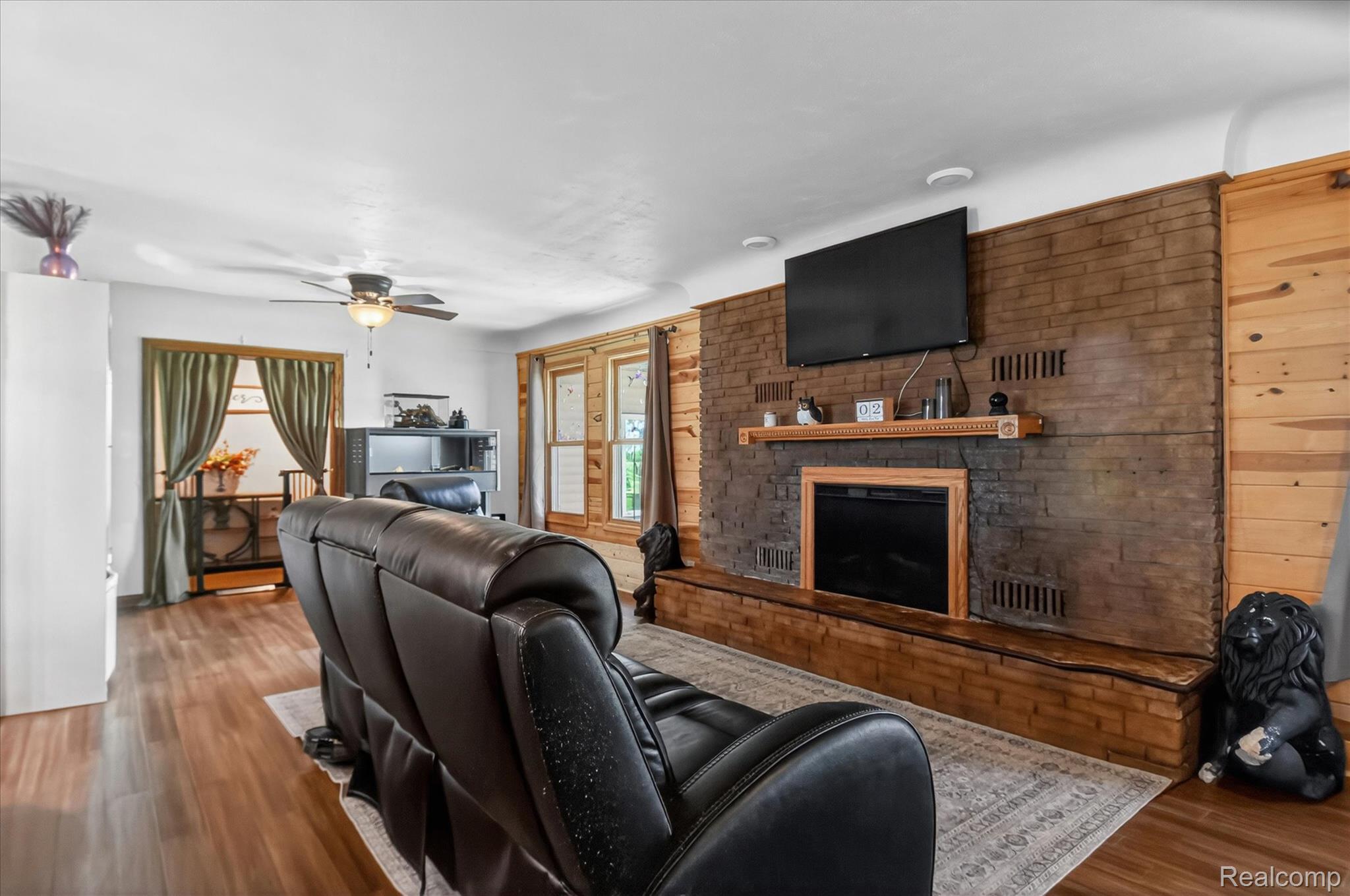 3949 West Burns Line Road Brown City, MI 48416 - Photo 13 of 70 Spacious living area featuring a brick accent wall with an integrated fireplace and mantel